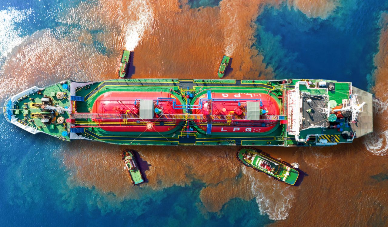 An aerial view of an oil tanker spilling oil into the sea.