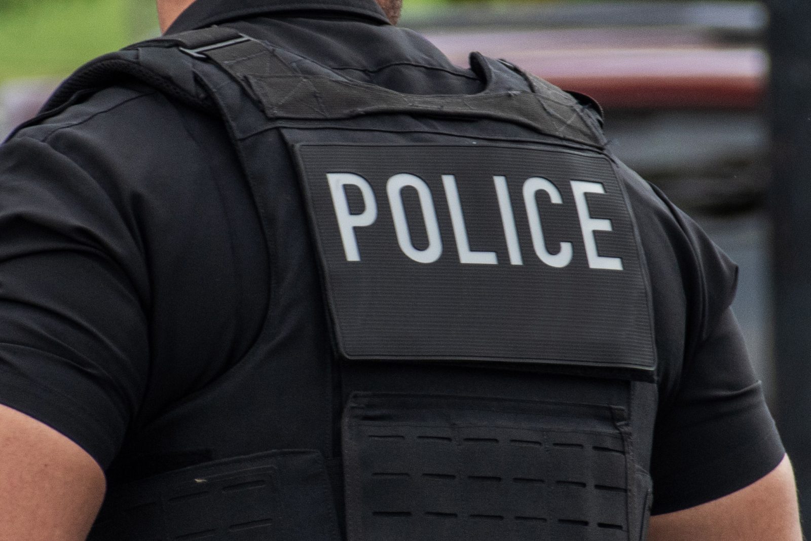 Close-up of the word "police" printed on the back of an officer's uniform.
