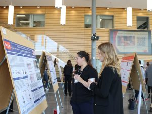 Two university students look at a research poster at a conference.
