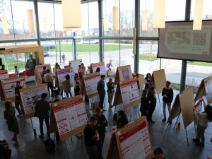An aerial view of a posters being set up at a conference in a bright atrium.