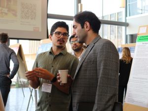 Two university students look at a research poster at a conference.