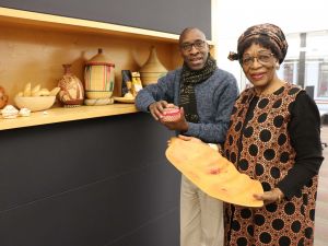 Brock Associate Professor of Linguistics Jean Ntakirutimana and Sofifran Executive Director Fete Ngira-Batware Kimpiobi stand next to a display case embedded in a wall containing a variety of African objects.