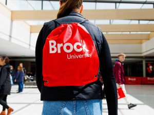 A woman tours a brightly lit space with a red napsack inside Brock University’s main campus.