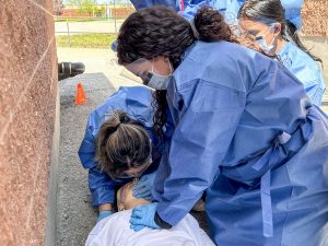 Brock Nursing students perform CPR on an unresponsive mannequin patient.