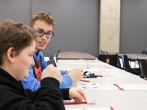 Two blind students make DNA codes from marshmallows and toothpicks in a classroom.