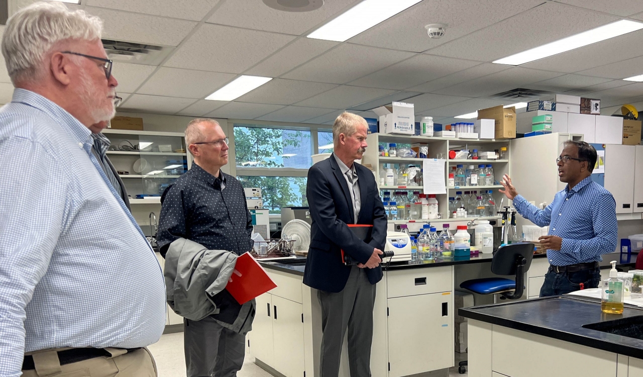 A man speaks to three other men in a lab.