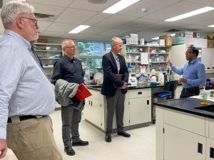 A man speaks to three other men in a lab.