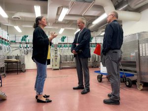 A woman speaks to two men in a lab.