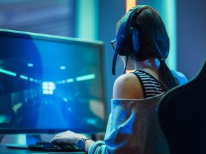 A woman is seen from behind playing a video game, which can be seen on the monitor in front of her.