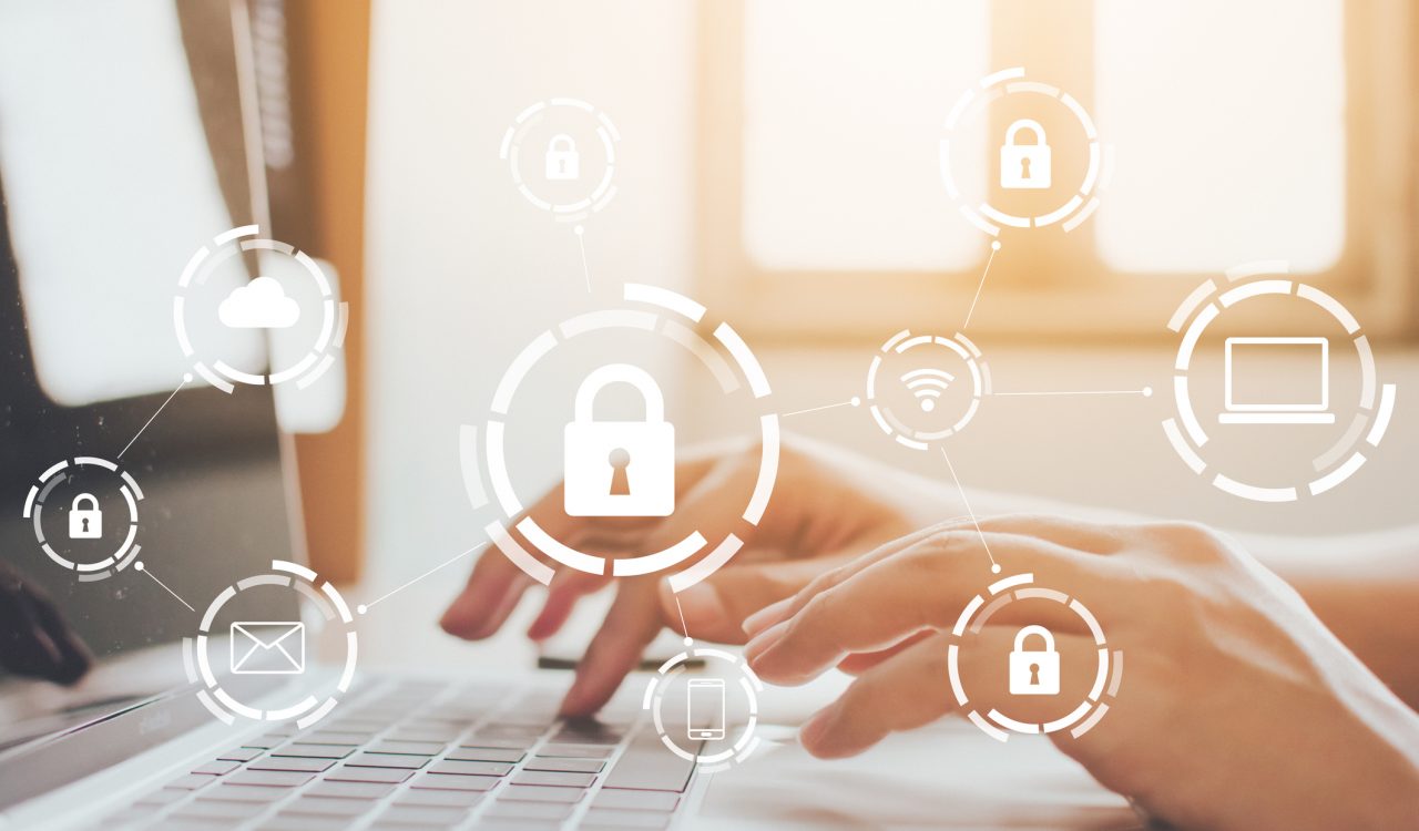 Closeup view of hands typing on a laptop with cybersecurity icons floating above them.