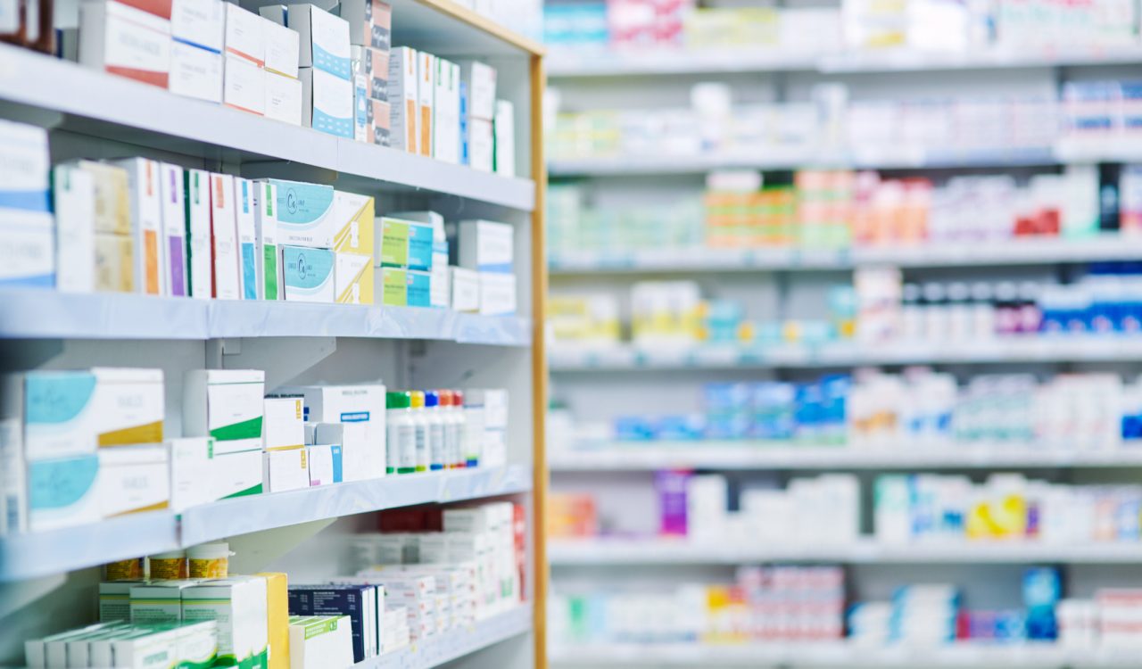 Aisle in a drugstore showing medications and pharmaceutical drugs stocked on shelves.