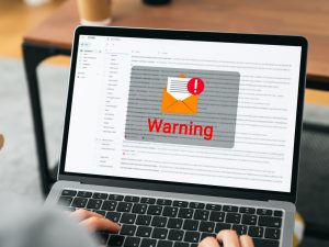 The word "warning" appears with an email icon on a laptop screen.