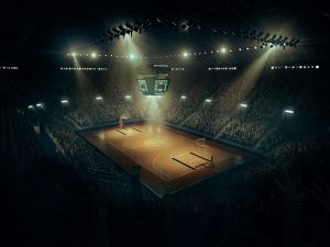 An indoor spotlit basketball arena full of spectators.
