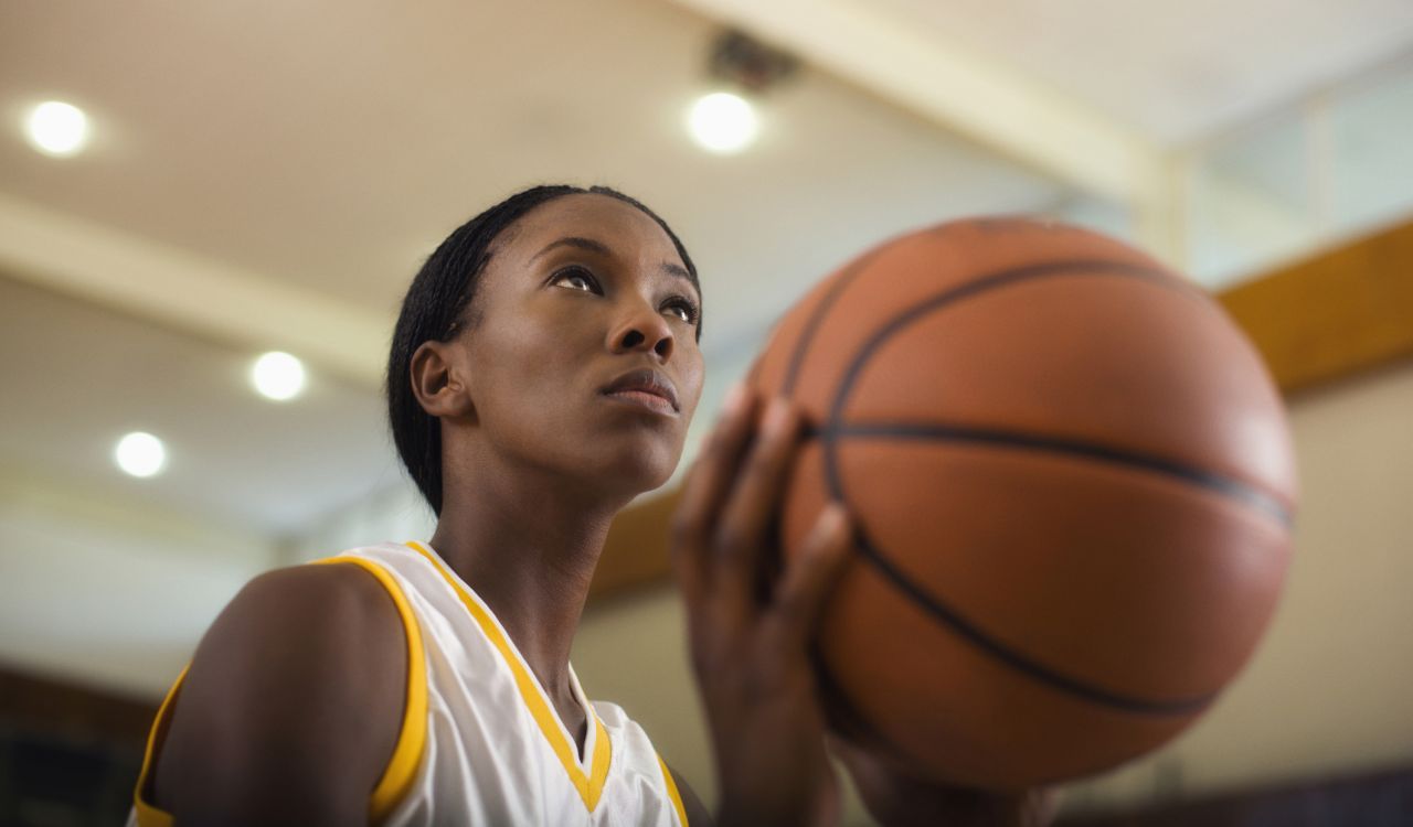 A close-up of a woman holding a basketball.