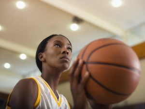 A close-up of a woman holding a basketball.