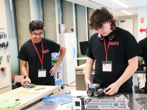 Two students build a motorized robot vehicle.