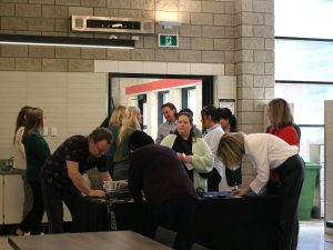A group of people fill out tickets on a table near the entrance to a campus cafeteria.