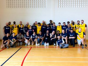 A large group of people in athletic gear pose for a photo in a gymnasium.