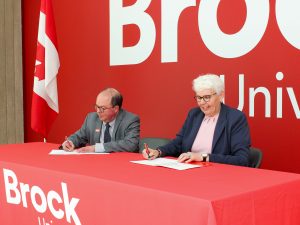 Two people sign papers at a table.