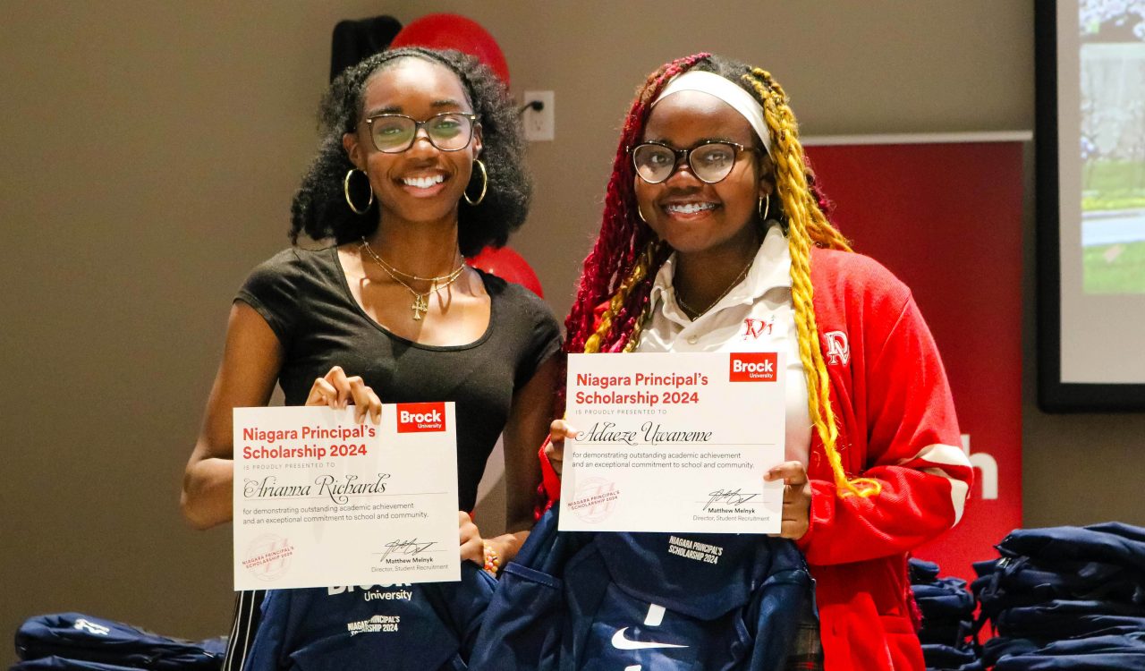 Two high school students pose for a photo holding certificates.