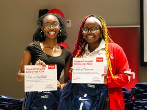 Two high school students pose for a photo holding certificates.