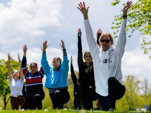 Brock University employees take part in an outdoor yoga session among cherry blossom trees and sunny weather.