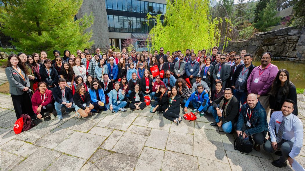 A large group of people poses in front of a pond in a courtyard.