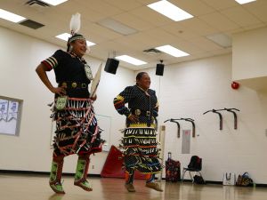 Two First Nations women wearing traditional regalia perform a jingle dress dance performance.