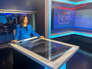 Alessandra Carneiro seated at a glass anchor desk with studio equipment visible and the CTV News Channel logo on the wall.