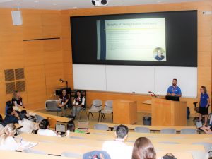 Group of presenters give a presentation in a lecture hall.