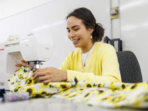 A female First Nations university student makes a traditional ribbon skirt on a sewing machine.