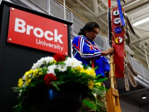 A man stands holding Brock's sacred Eagle Staff.