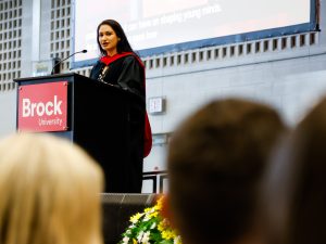 A woman speaks at a podium in front of a crowd of people.