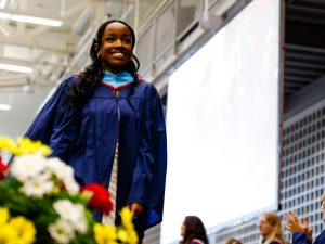 A woman wearing a graduation gown crossed the Convocation stage.