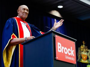 A man stands at a podium with his hand raised speaking to an unseen crowd.