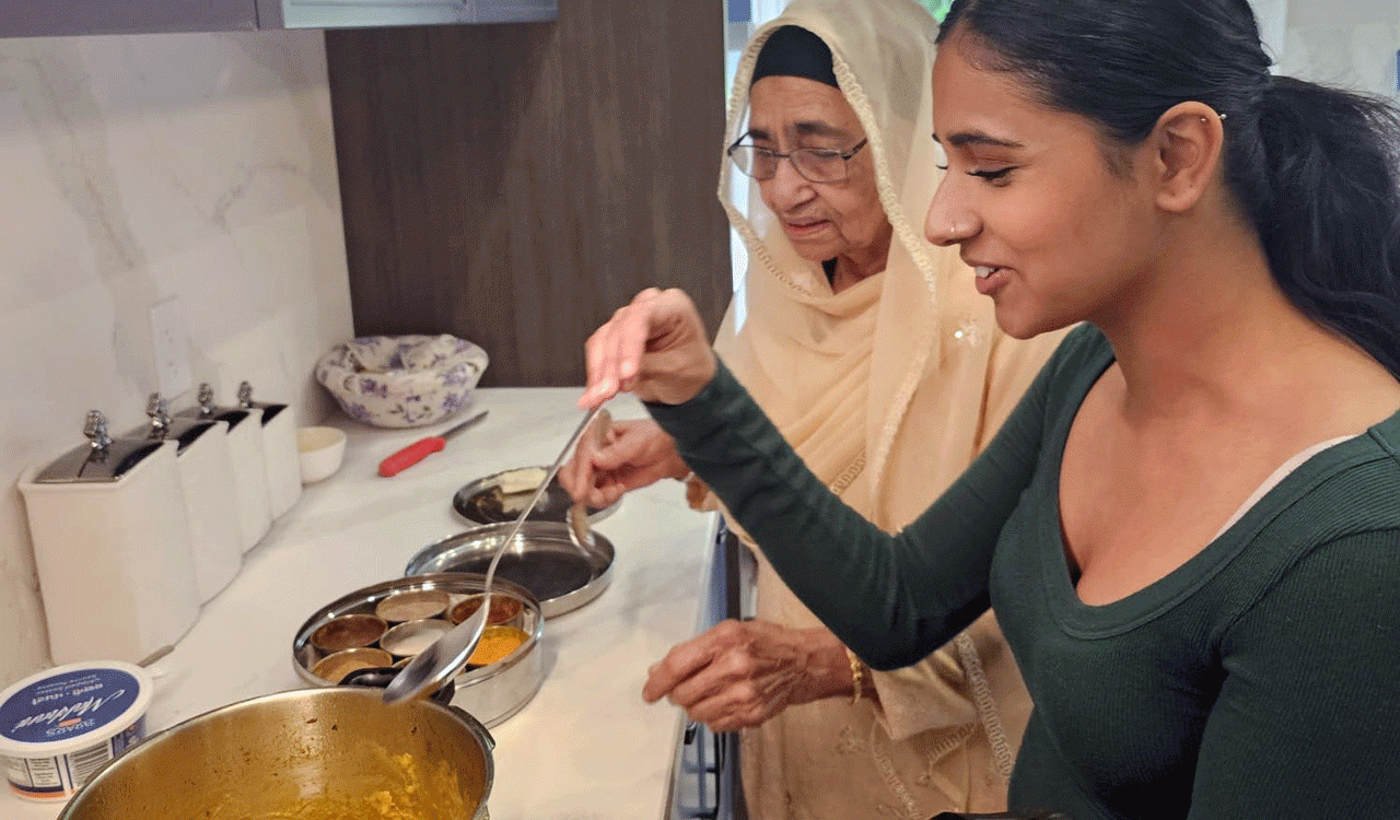 Honours Bachelor of Public Health graduate Gehreen Brar holds a metal spoon that she is dipping into a pot on the stove while her grandmother Lakhwinder Kaur Brar looks on.