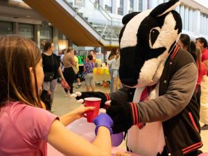 A mascot of a badger grabs a glass of lemonade from a fourth-grade student.