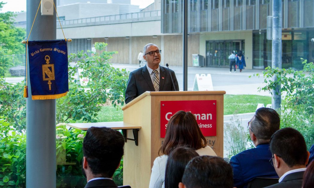 A man stands at podium speaking to an audience.