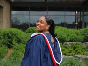 A person wearing wearing a blue academic robe smiles over her shoulder for the camera.