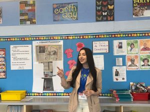 Brock University Biological Sciences student Alexandra Leone engages children in an interactive science-based activity. She is speaking at the front of an elementary school classroom.