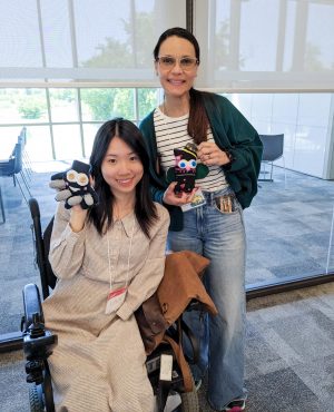 Two female university students pose for a photo with sock owls made during a crafting workshop.