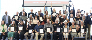 A large group of people poses for a photo while holding certificates.