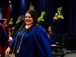 Samantha Bowman smiles while wearing a blue graduation gown on the stage at Brock University's 115th Convocation ceremonies.