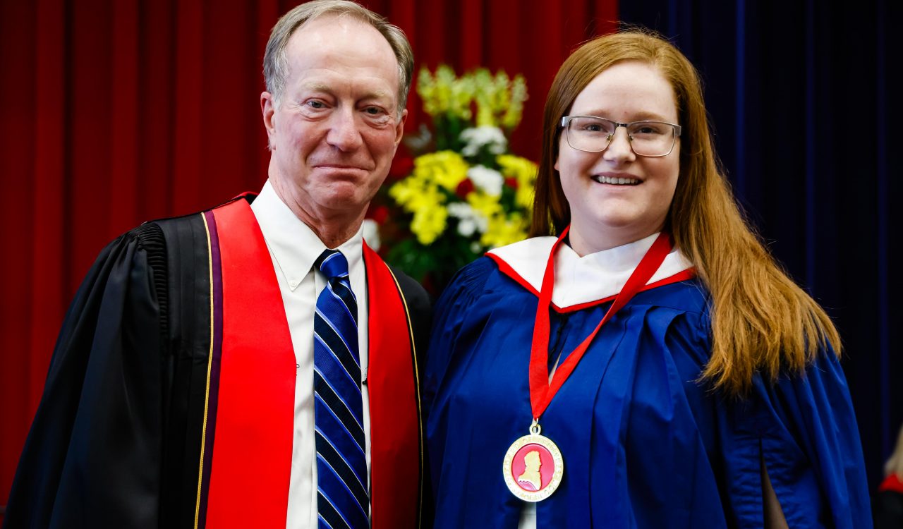 A man and woman stand on stage with a medal during Brock University’s convocation.