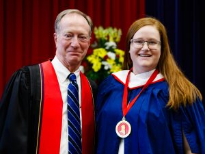 A man and woman stand on stage with a medal during Brock University’s convocation.