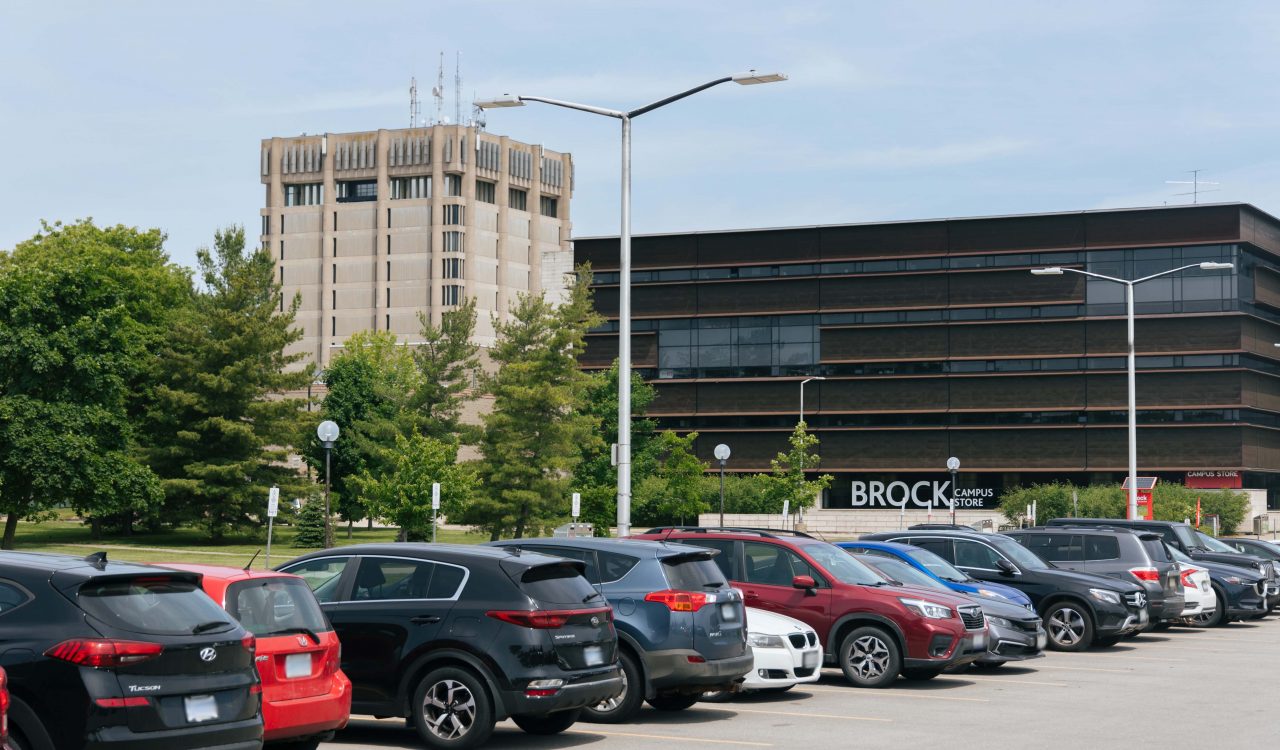 A parking lot filled with vehicles with the Campus Store in the background.