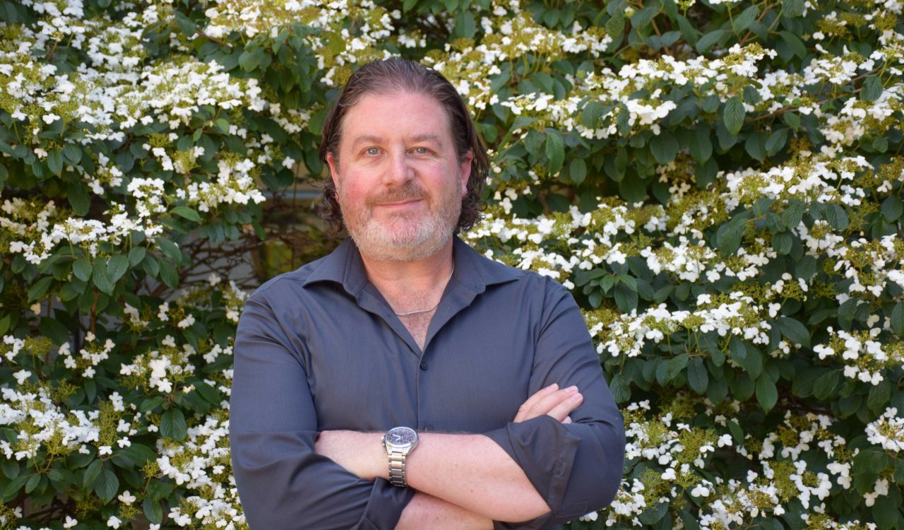 Gordon Hodson in front of a flowering tree on Brock’s main campus.