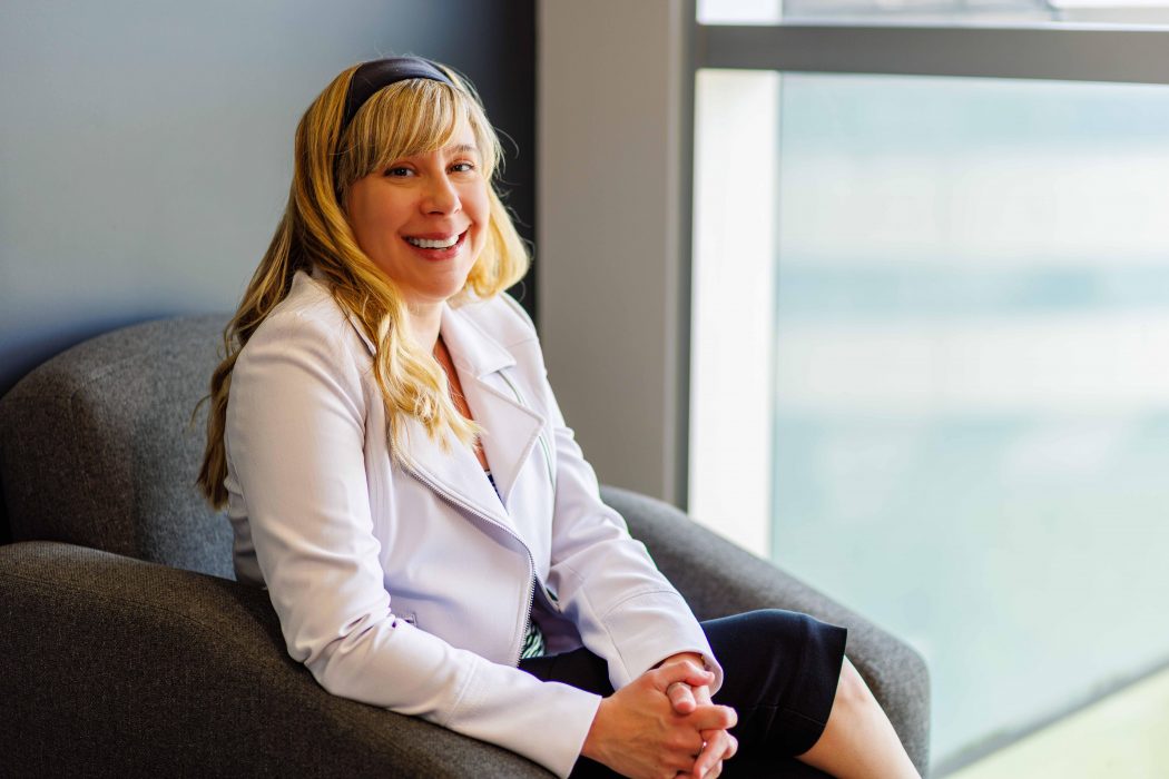 Danielle Sirianni Molnar, Canada Research Chair in Adjustment and Well-Being in Children and Youth, sits in a chair next to a window.