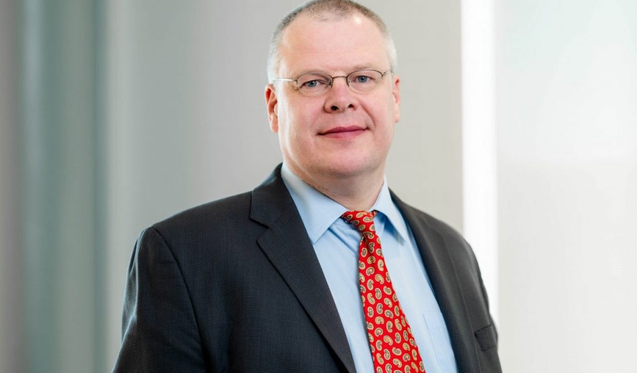 A man poses for a headshot in a suit.