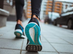 Close-up of running shoes as someone walks on a sidewalk.